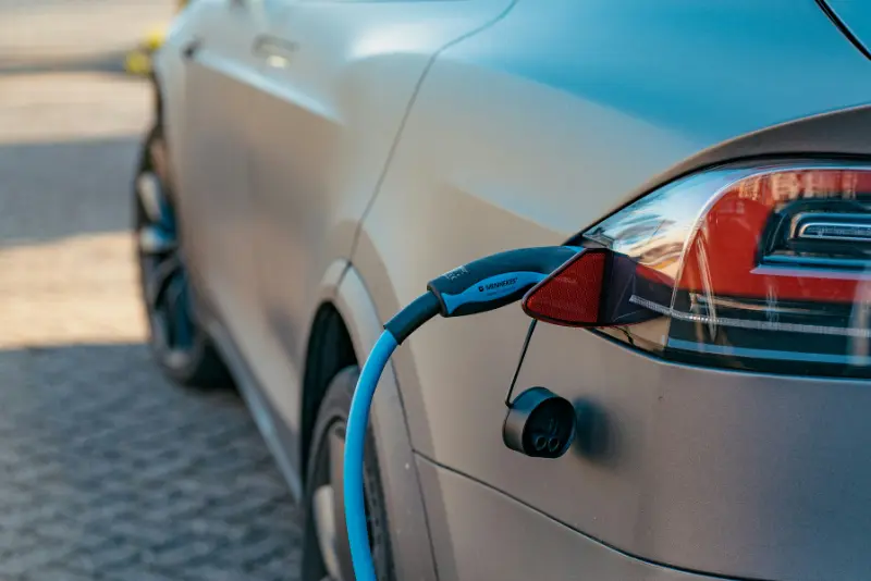 Blue electric vehicle charging cable plugged into the rear charging port of a silver electric car