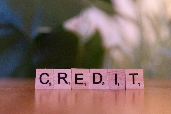 Wooden Scrabble letter tiles spelling out CREDIT on a table — a visual reference to how credit score affects loan options.